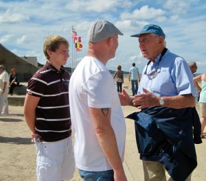 two younger men speak with an older man who served in WWII
