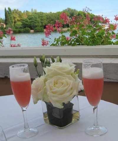 Drinks in fluted glasses with a floral centerpiece overlooking a lagoon as part of a travel bucket list