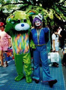 Woman in blue jump suit and clown makeup standing next to person in green bunny suit in Singapore