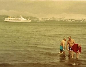 family in ocean with boat background