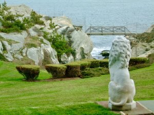 lion statue overlooking bushes, lake and bridge